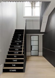 Modern staircase featuring glass stair risers printed with an inspirational quote about success.