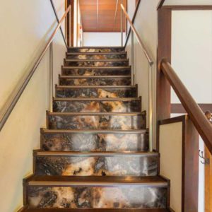 Luxury interior staircase showcasing glass risers with a deep, sophisticated marble stone texture.